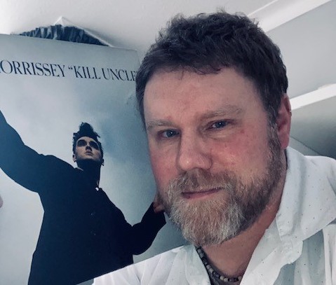 A man holds Morrissey's Kill Uncle vinyl close to his face